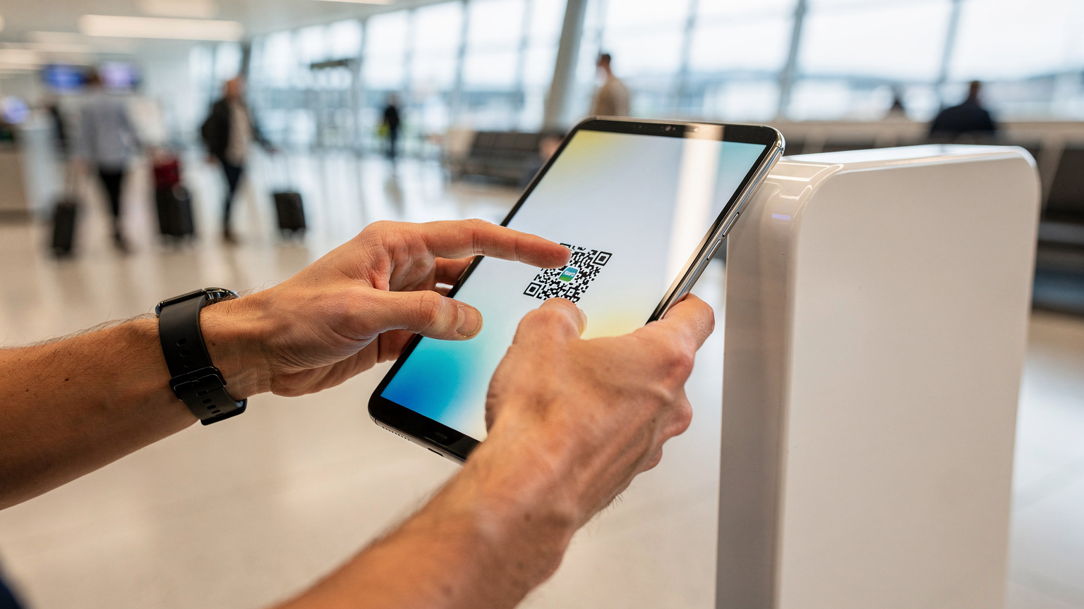 En reisende peker på en QR-kode for eSIM-aktivering på en skjerm i en moderne, lys flyplassterminal.